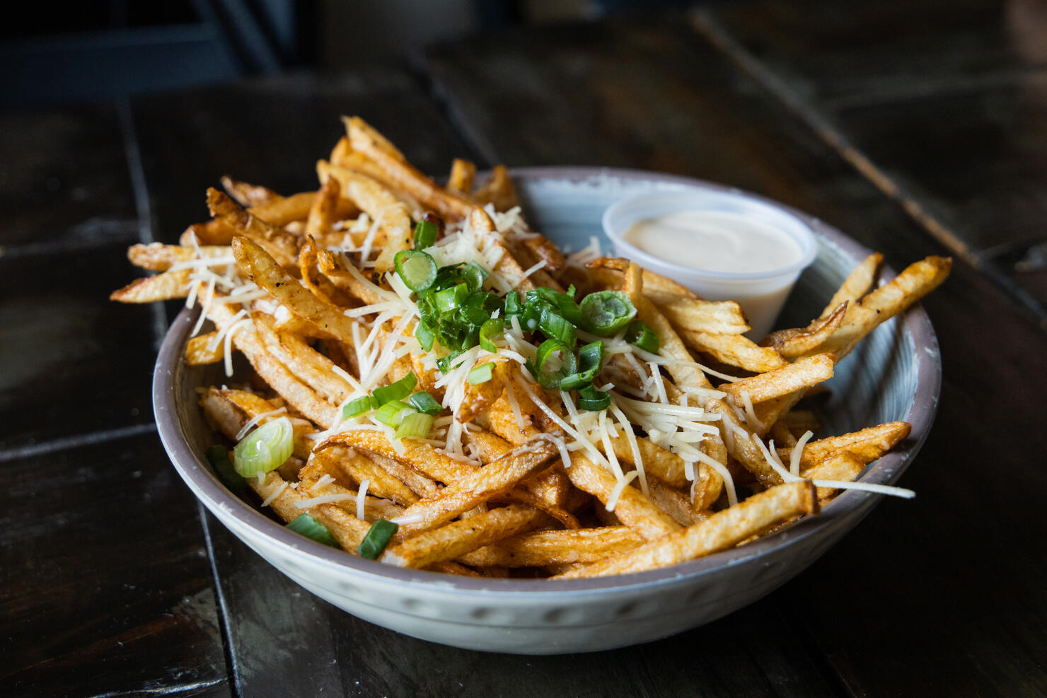 A large bowl of gourmet black truffle french fries in a bowl sprinkled with shredded parmesan cheese.