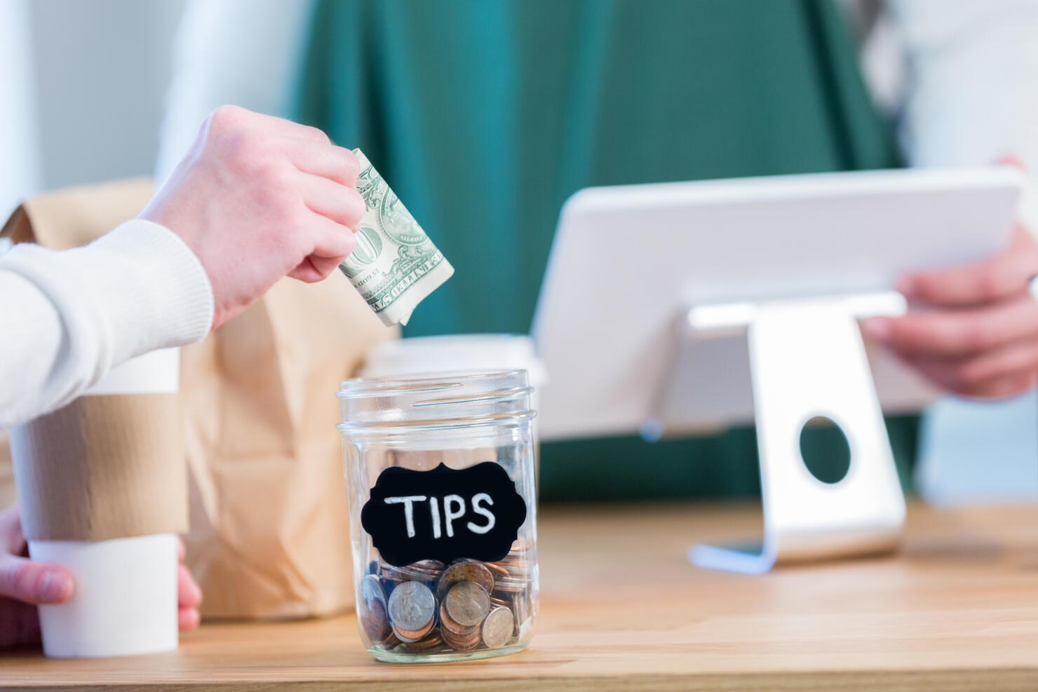 Unrecognizable coffee shop customer using tip jar
