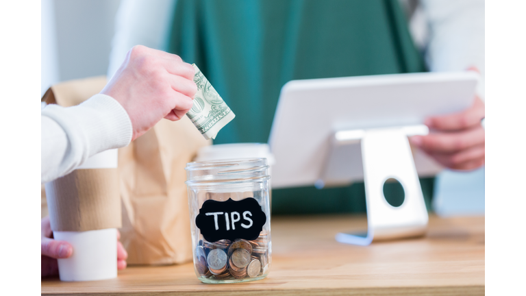 Unrecognizable coffee shop customer using tip jar