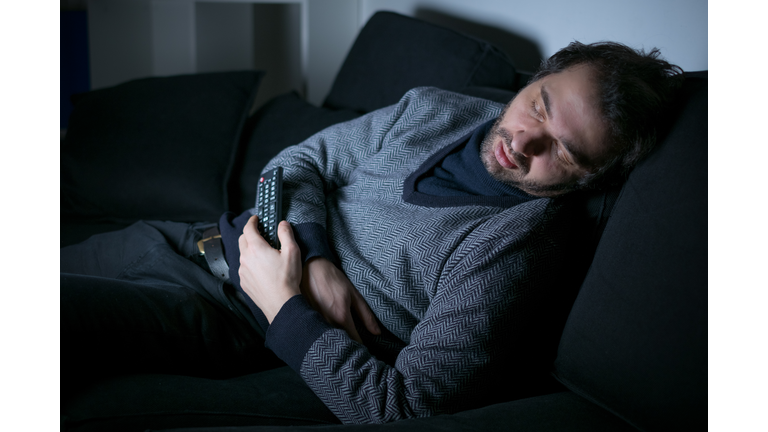 Tired man sleeping in front of the tv screen
