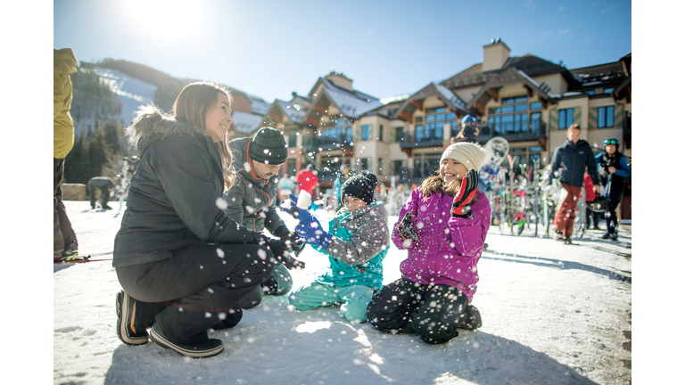 Hispanic family throwing snow and having fun on a nice sunny day at a ski resort.