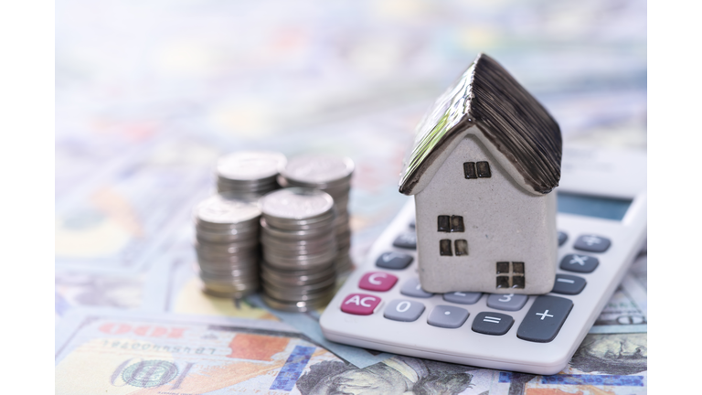 The house is on the calculator and the coins are on the calculator. Coin savings plan to buy home ideas for property stairs, mortgage and real estate investment savings for home purchase.