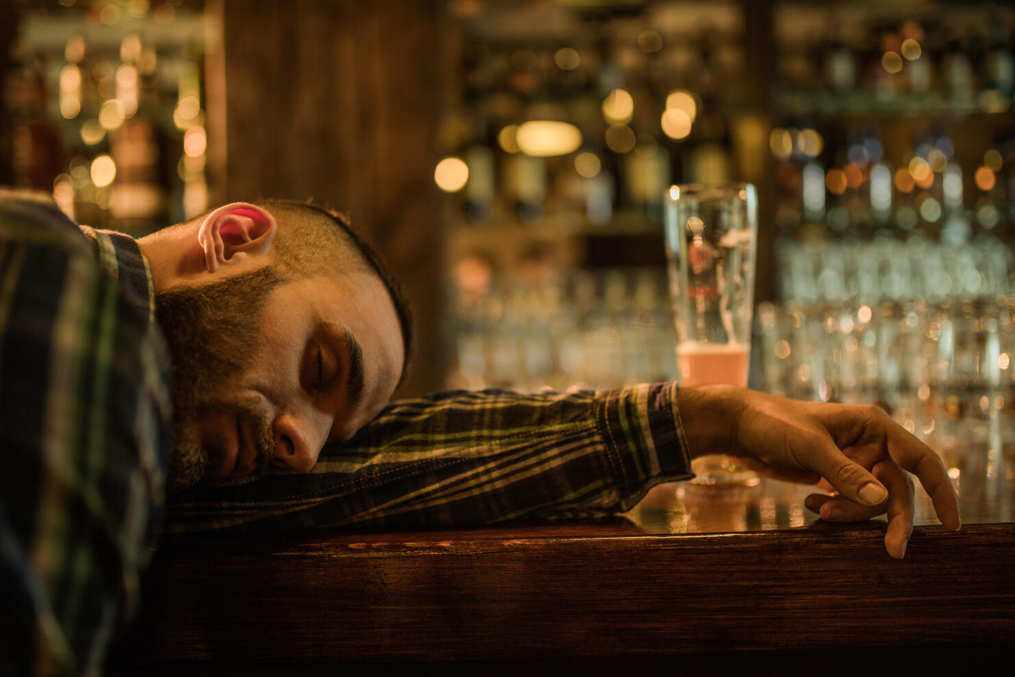 Young wasted men fell asleep on a bar counter in a pub.