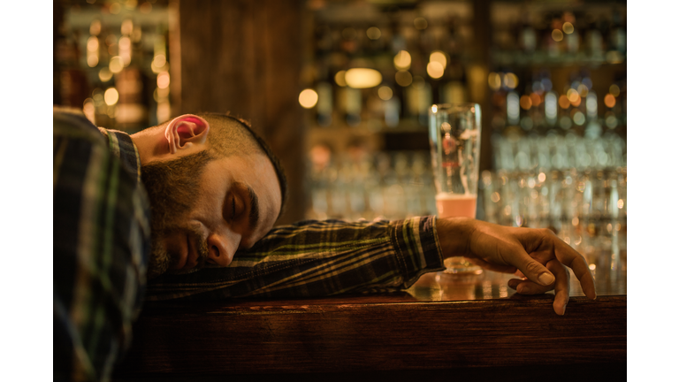 Young wasted men fell asleep on a bar counter in a pub.