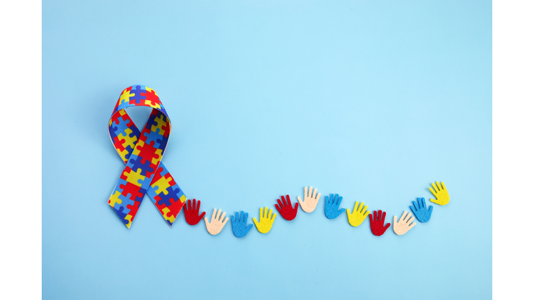 Autism awareness concept with colorful hands on blue background. Top view