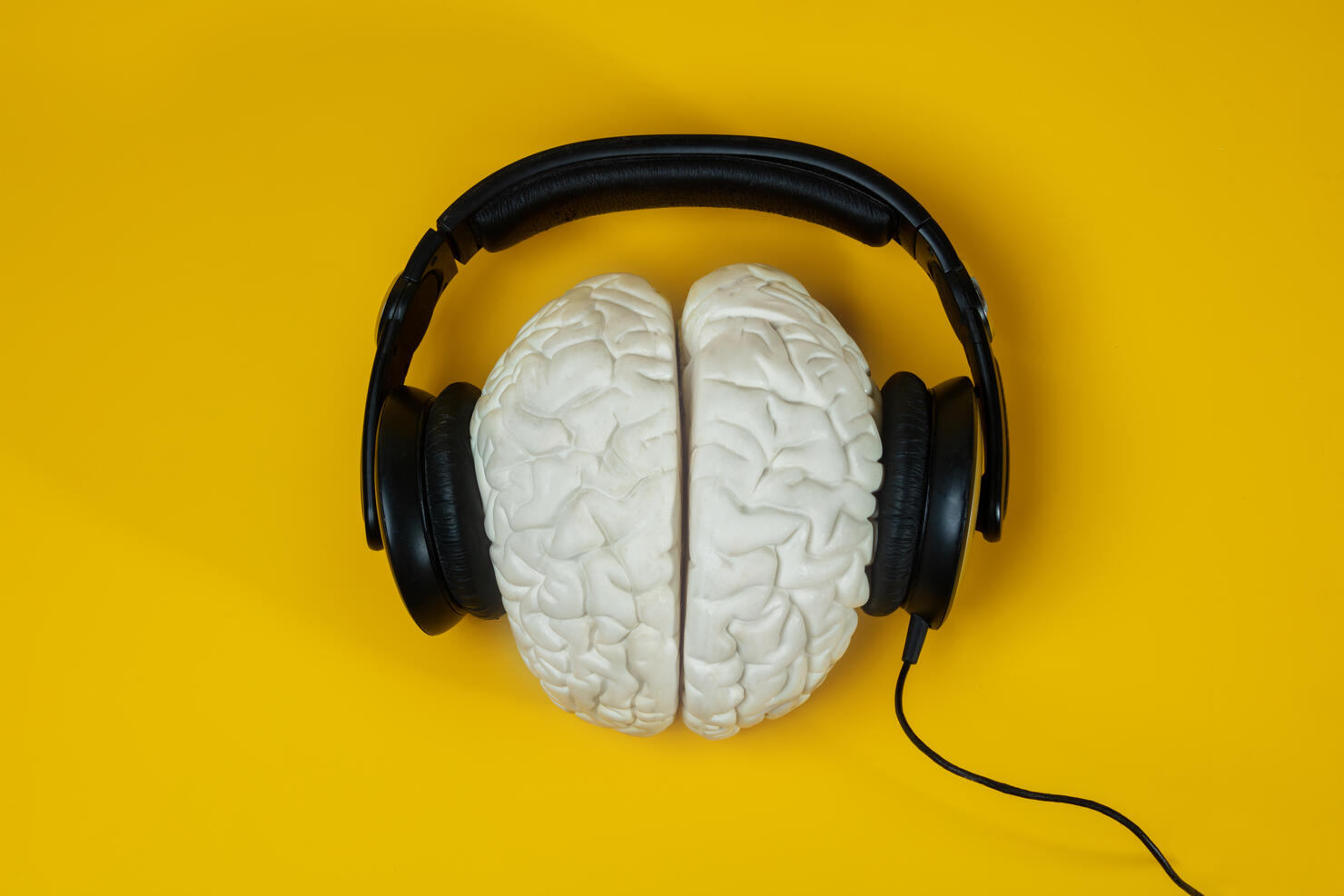 Headphones on the brain over yellow background
