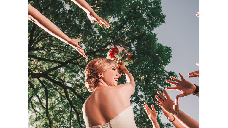 cheerful bride throws a wedding bouquet to her friends.