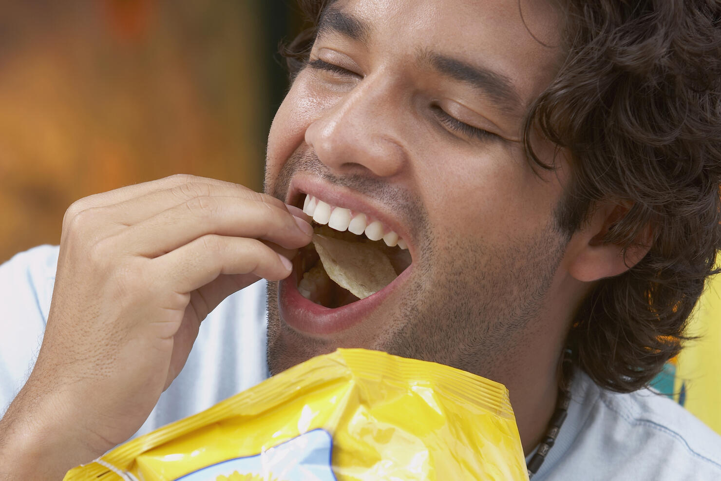 Close-up of a young man eating potato chips