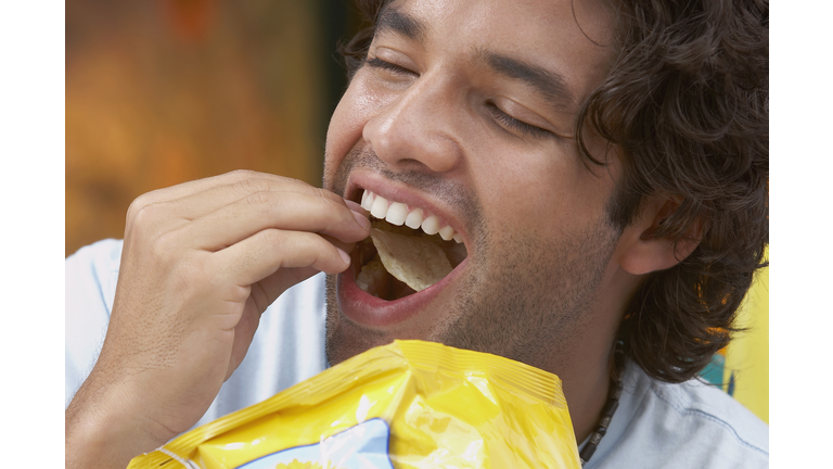 Close-up of a young man eating potato chips