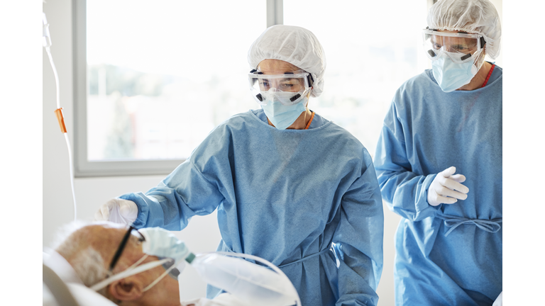 Doctors examining patient in ward during COVID-19