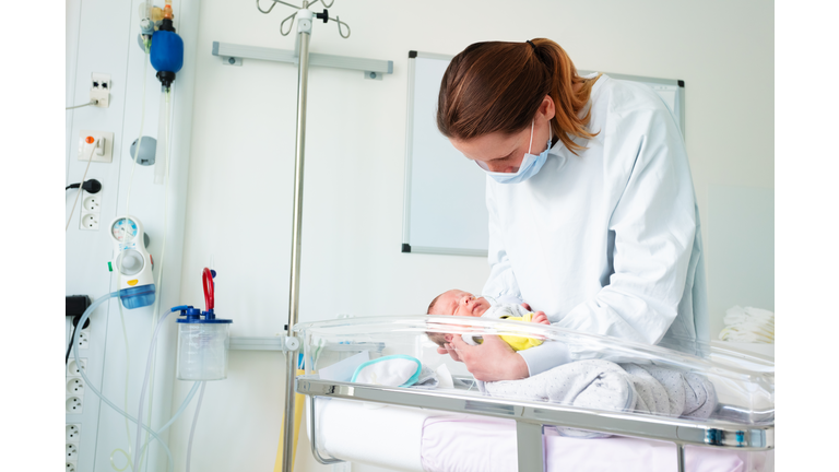 Nurse in ICU examining premature born infant
