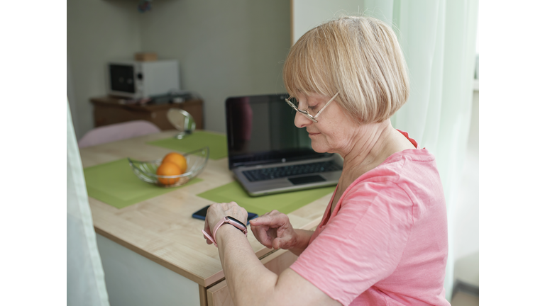 Senior woman checking health information using smart watch, modern healthcare and support
