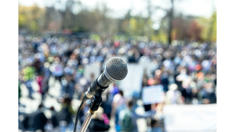 Protest or public demonstration, focus on microphone, blurred group of people in the background