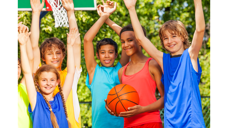 Friends hold arms up at basketball game