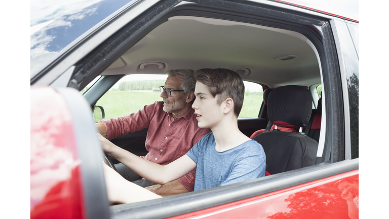 Father teaching son driving a car