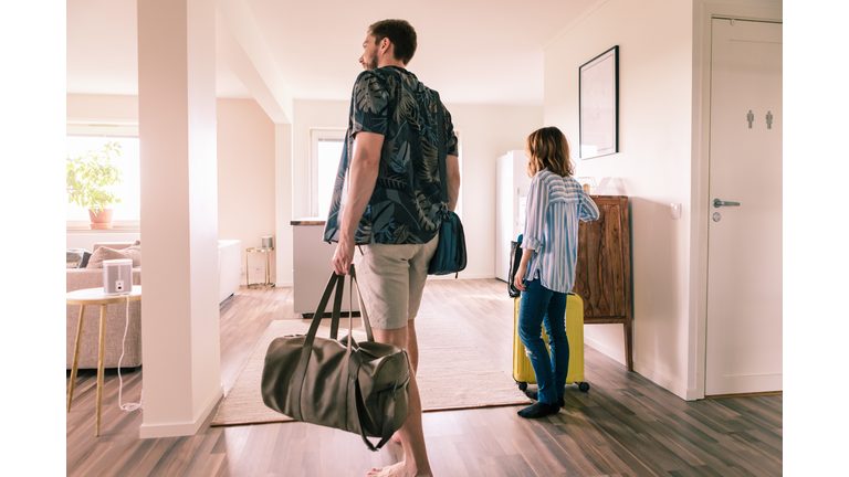 Couple walking with luggage in apartment during staycation