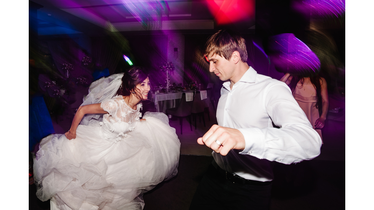 Wedding dance of newlywed and people. bride and groom dancing in restaurant. Wedding couple dancing in smoke and colored lights.