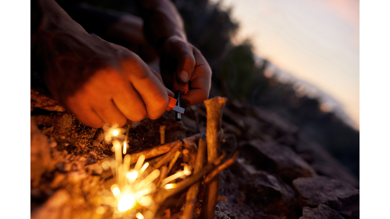 Close up of male hands making a fire with flint and steel in the wild