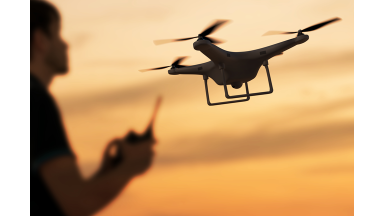 Man is controlling flying drone at sunset. 3D rendered illustration of drone.