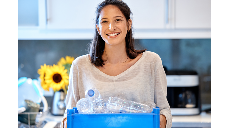 Shot of a young woman getting ready to recycle some bottles at home