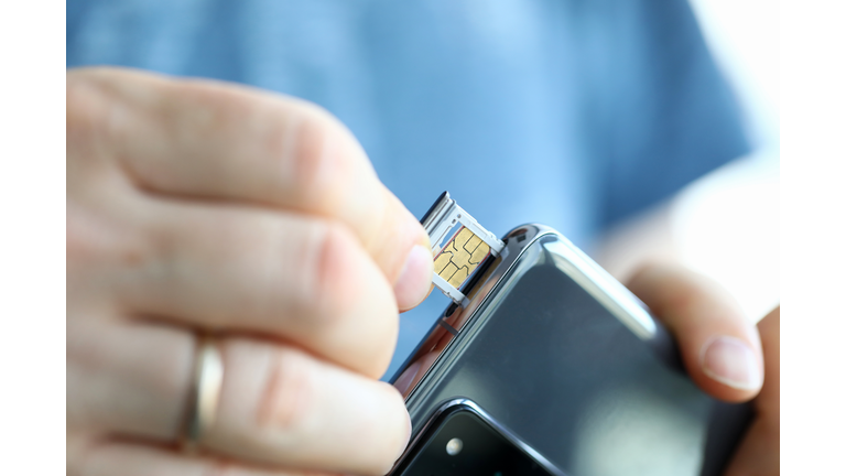 Male hands getting sim card slot of his smartphone out