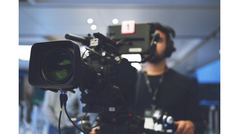 Professional cameraman with headphones with HD camcorder in live television