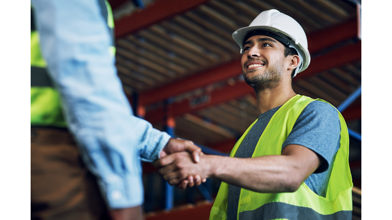 Shot of two builders shaking hands at a construction site