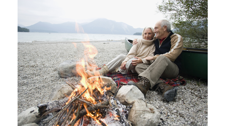 Germany, Bavaria, Senior couple sitting at campfire