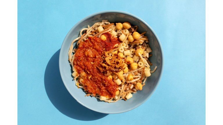 Egyptian national Koshari food in a turquoise plate on blue background