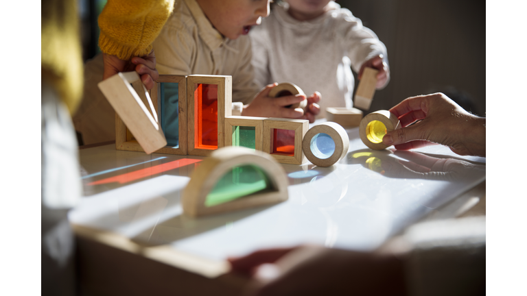 Little kids playing with colorful wooden building blocks on the table