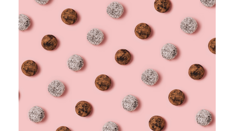 Healthy natural candies homemade from natural ingredients, handmade energy ball with dried fruits. Vegan sweets on pastel pink background. Top view. Flat lay. Food concept.