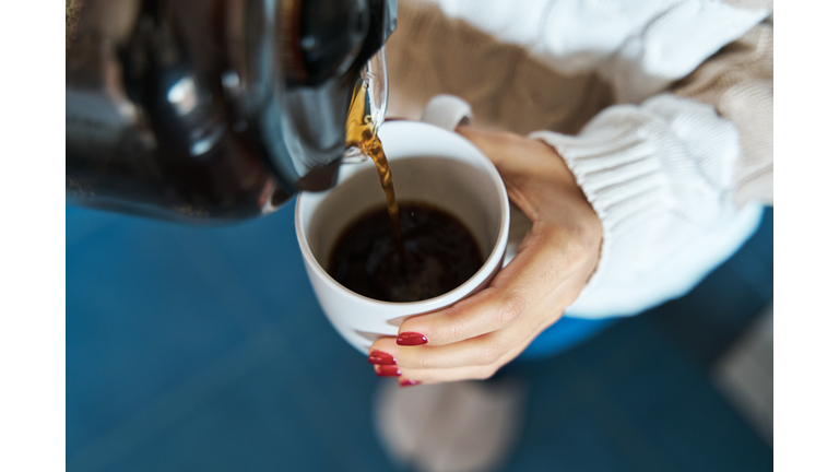 Woman pouring herself hot coffee to a mug.