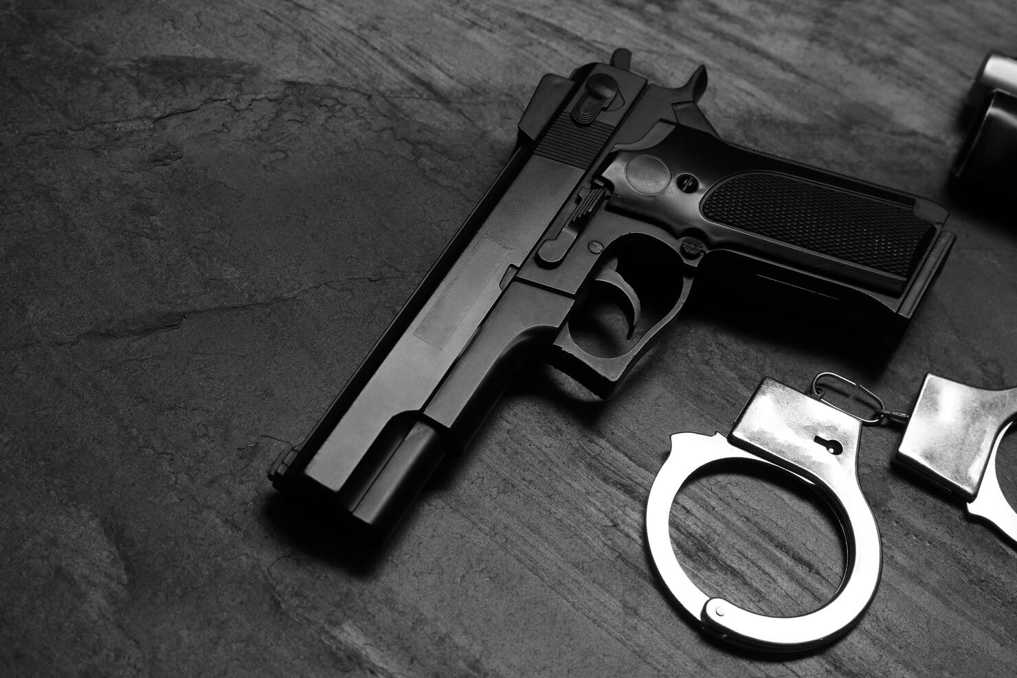 Gun and handcuffs on dark table, space for text
