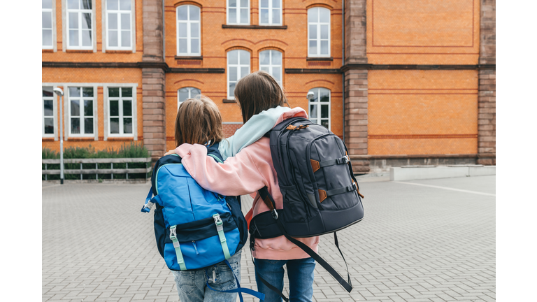 Teenage girls walk in an embrace and go to school at the beginning of the lessons.