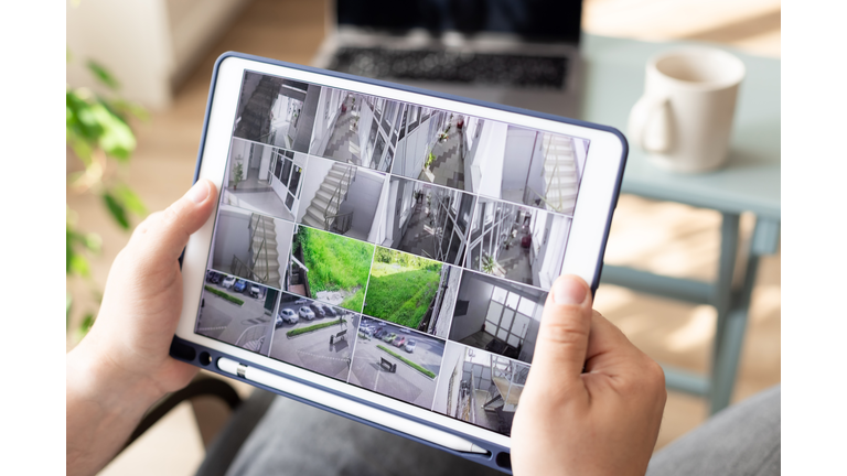 Man monitoring modern cctv cameras on digital tablet indoors