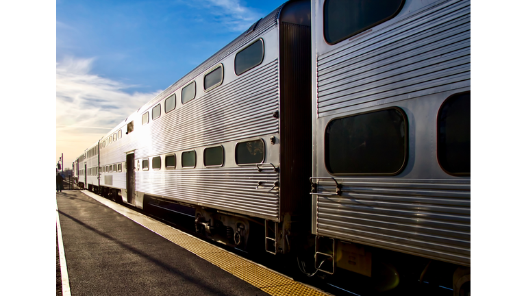 Train leaving station and disappearing into sunset at rush hour