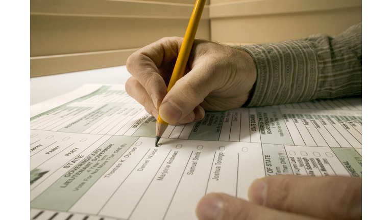 Man marking election ballot with pencil, close-up of hands