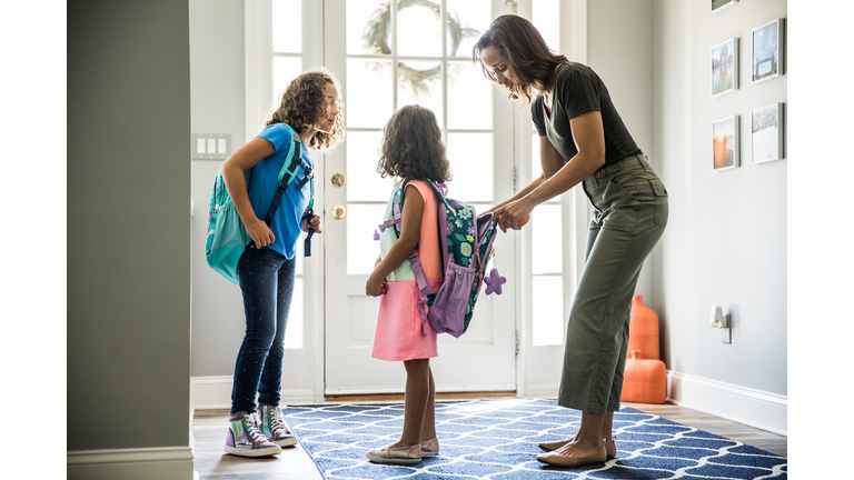 Mother packing daughters backpacks for school
