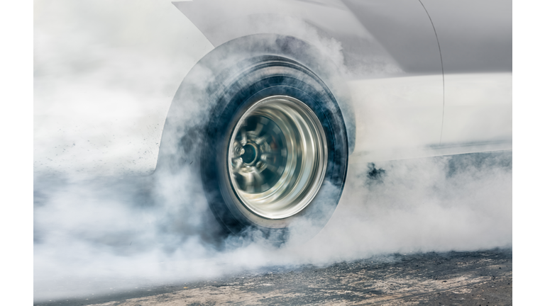 Drag racing car burns rubber off its tires in preparation for the race