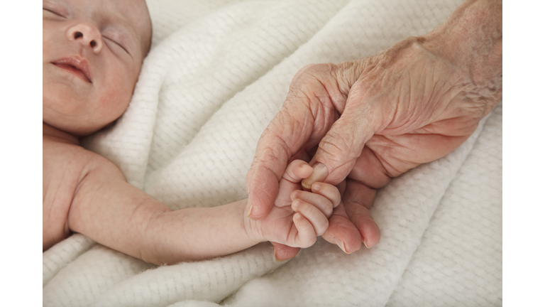 sleeping baby holding great grandmother's hand