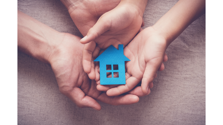 Adult and child hands holding paper house, family home and homeless shelter concept