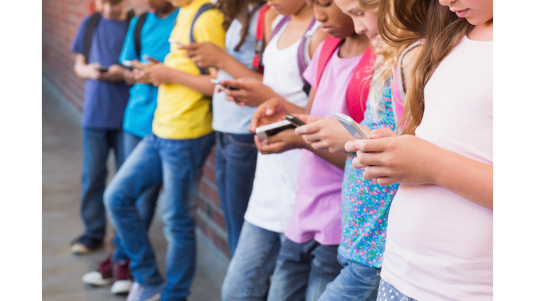 Cute pupils using mobile phone