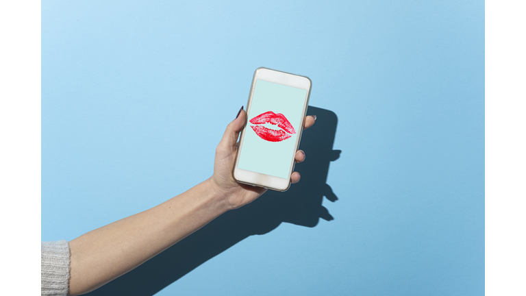 Woman's hand shows her smartphone with Lipstick kiss