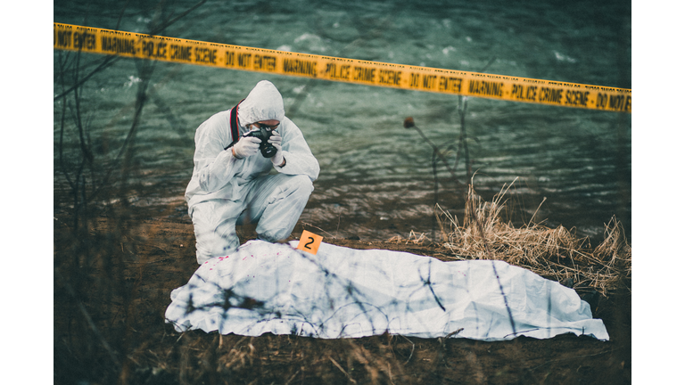 Photographer taking photos of crime scene by the river