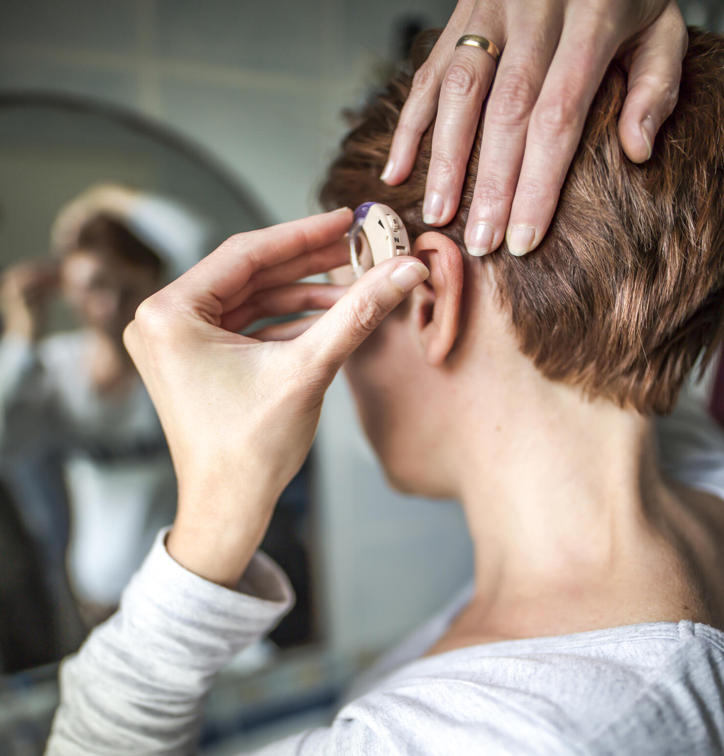 Women inserting hearing aid. Medical concept