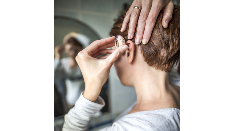 Women inserting hearing aid. Medical concept