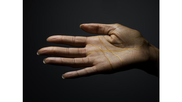 Female dark skinned hand covered with gold lines