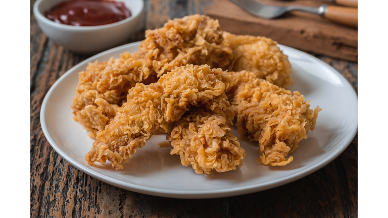 Crispy fried breaded chicken strips on plate and ketchup