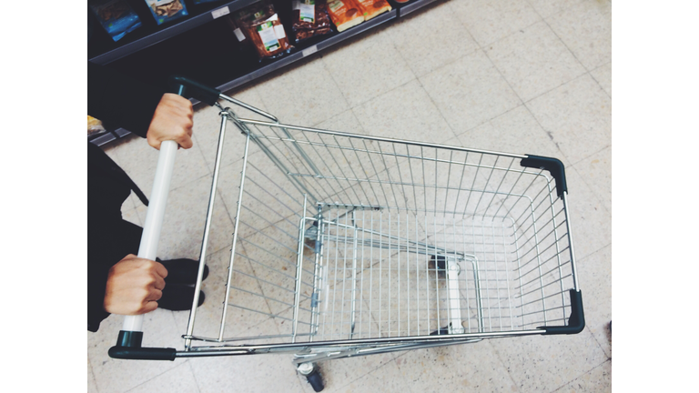 Low Section Of Woman Walking With Shopping Cart On Floor In Supermarket