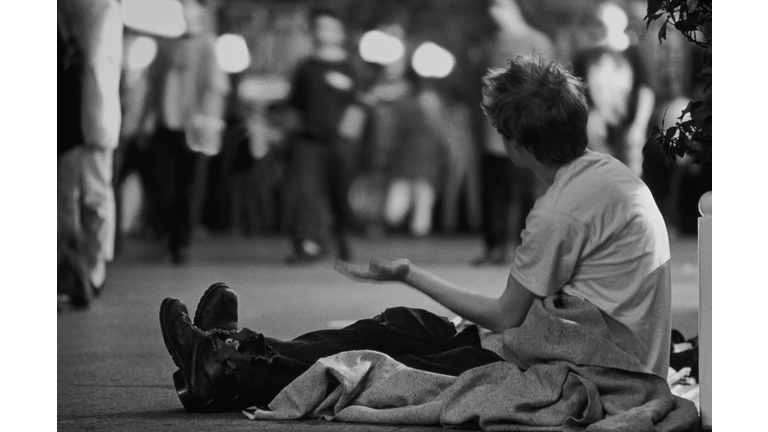 Homeless man begging on street at night (B&W)
